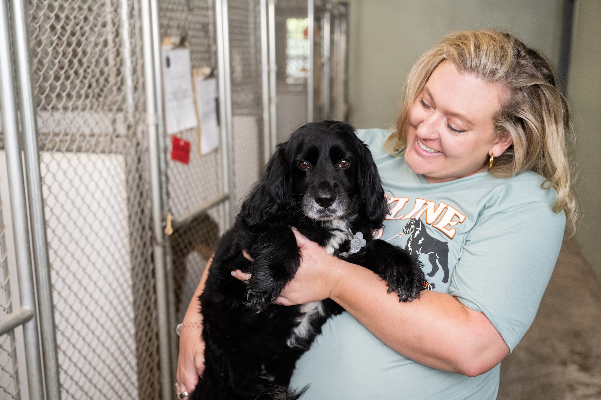 Staff member holding black dog and smiling at Hyline Hotel for Dog Boarding near Blaine, WA